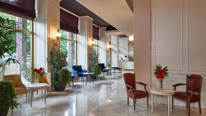 A spacious lobby with a polished floor, comfortable seating areas, and large windows allowing natural light. - Hotel Astoria (Biella)