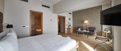 Una habitación de hotel con una cama grande, un escritorio con una silla, un televisor y un papel tapiz decorado.