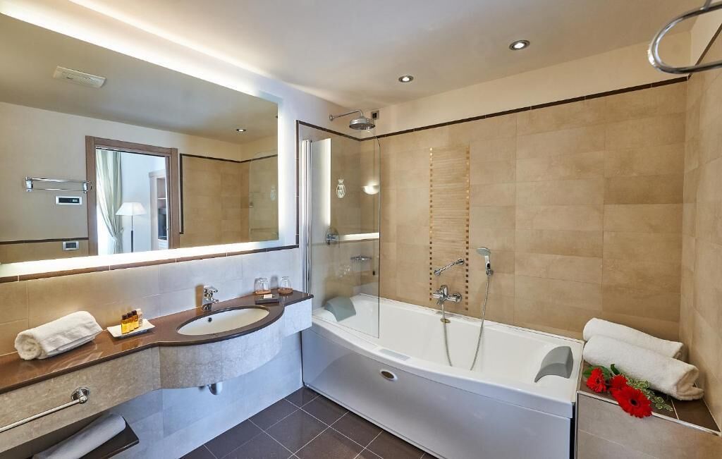 Un baño moderno con una bañera grande, una zona de ducha separada y un tocador con lavabo y espejo.