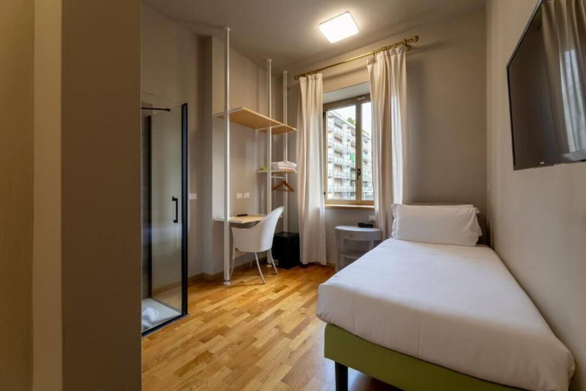 A compact hotel room with a bed, a desk, and a chair.