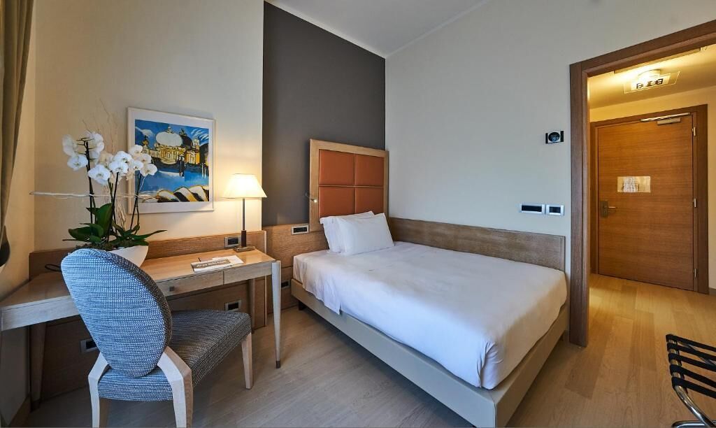 Ein Hotelzimmer mit Bett, Schreibtisch, Stuhl und einem Bild an der Wand.
