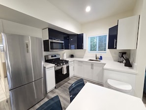 A compact kitchen with a refrigerator, stove, microwave, and sink.