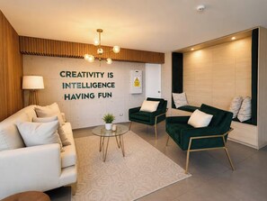 Una sala de estar moderna con un sofá, dos sillones, una mesa de centro y una pared con texto motivacional.