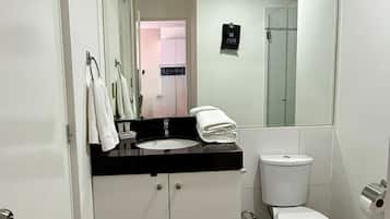 Un baño moderno con un lavabo blanco, un inodoro y un espejo grande.