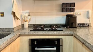 Een keuken met witte kastjes, een rvs afzuigkap, een inbouwoven en een aanrecht met een koffiezetapparaat.