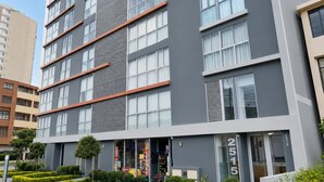 A multi-story building with a modern architectural design, featuring a prominent entrance with glass doors and a visible address number. - APT LOCK - LINCE (Lima)