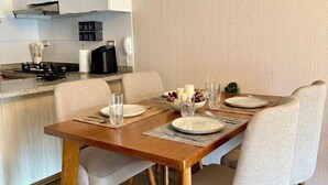 Een moderne keuken met witte kasten, een eettafel gedekt met borden, glazen en een kaars.