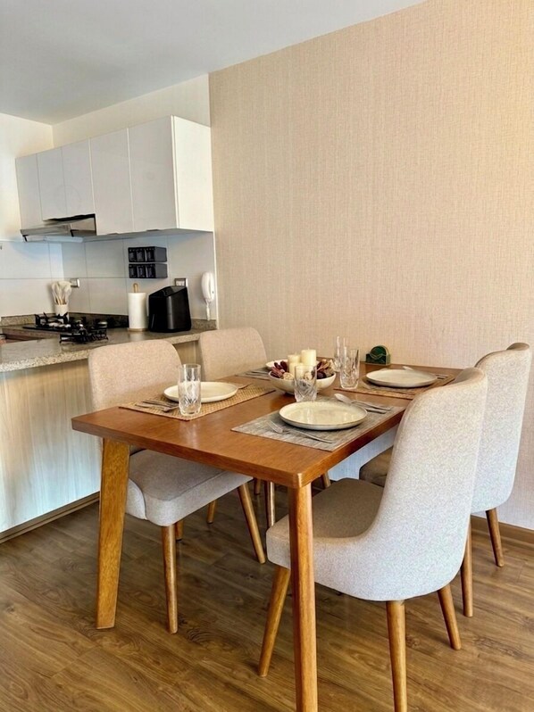 Cozinha moderna com armários brancos, uma mesa de jantar posta com pratos, copos e uma vela.