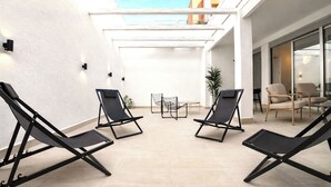 Terrassa exterior moderna amb seients de relaxació negres, una taula petita i una planta en test.