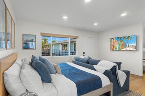 Un dormitorio con dos camas, un ventanal grande, un cuadro y vistas al exterior.