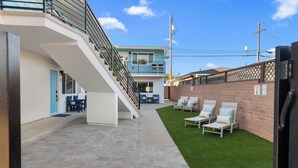 A modern building with a staircase, outdoor seating, and a fenced area.