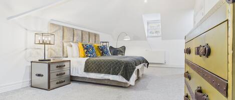 A bedroom with a bed, a dresser, a lamp, and a trunk.