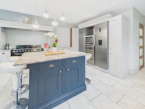 A modern kitchen with a central island, stainless steel appliances, and pendant lighting. - Harvax House (Chepstow)