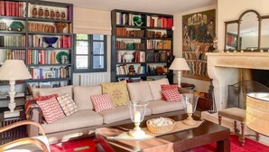 Una sala de estar acogedora con un sofá, una mesita de centro y estanterías llenas de libros.