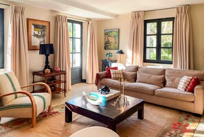 Una sala de estar con sofá, sillón, mesa de centro y estantería.