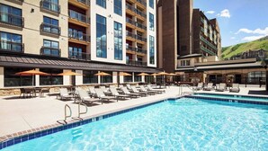Ein Hotel mit Schwimmbad, Liegestühlen und Sonnenschirmen.