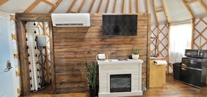 Une pièce chaleureuse avec un mur en bois, un téléviseur fixé au mur, une cheminée et un coin cuisine équipé d’un four à micro-ondes.