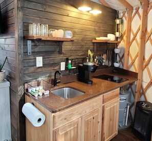 A kitchen with wooden cabinets, a double sink, and a countertop with various kitchen items.