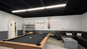 Una sala biliardo con tavolo da biliardo, divano e tavolino.