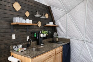 Una cocina con encimera de granito, cafetera y pileta.