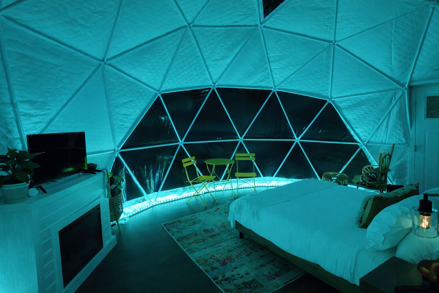 A room with a dome-shaped ceiling, a bed, a television, and a seating area with chairs.