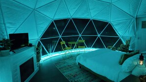 Una stanza con soffitto a cupola, un letto, una televisione e un’area salotto con poltrone.
