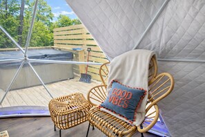A wicker chair with a cushion, a white tent-like structure, and a wooden deck. - The Penguin Igloo: Unique Geodesic Dome + Hot Tub (Logan)