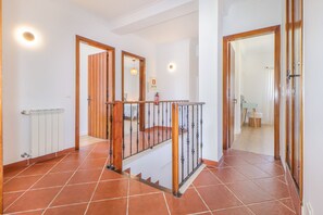 A hallway with a wooden staircase, tiled flooring, and a white radiator. - Villa Dos Amores - Heated swimming pool (Azeitão)