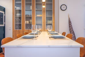 A dining area with a long table set for six, flanked by wooden cabinets with glass doors. - Villa Dos Amores - Heated swimming pool (Azeitão)