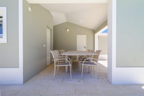 A dining area with a table and chairs, a door, and a light fixture on the wall. - Villa Dos Amores - Heated swimming pool (Azeitão)