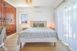A bedroom with a bed, wooden wardrobe, a window, and a bedside table. - Villa Dos Amores - Heated swimming pool (Azeitão)