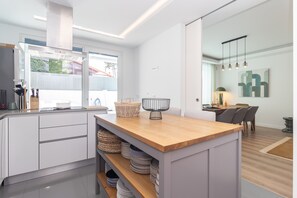 Eine moderne Küche mit weißen Schränken, einer Holzarbeitsplatte und einem Essbereich mit Tisch und Stühlen.