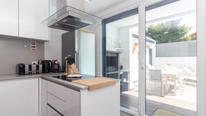 Een moderne keuken met een ingebouwde kookplaat, een houten snijplank en een glazen deur naar een terras.