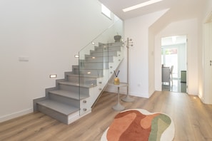 Eine moderne Treppe mit Glastrennwand, Holzboden und einem kleinen Tisch mit einer Vase.