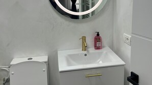 Une salle de bain avec des toilettes, un lavabo et un miroir.