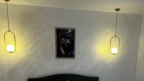 Un lit bien fait, avec du linge de lit blanc, deux tables de chevet avec des lampes et une œuvre d’art encadrée au mur.