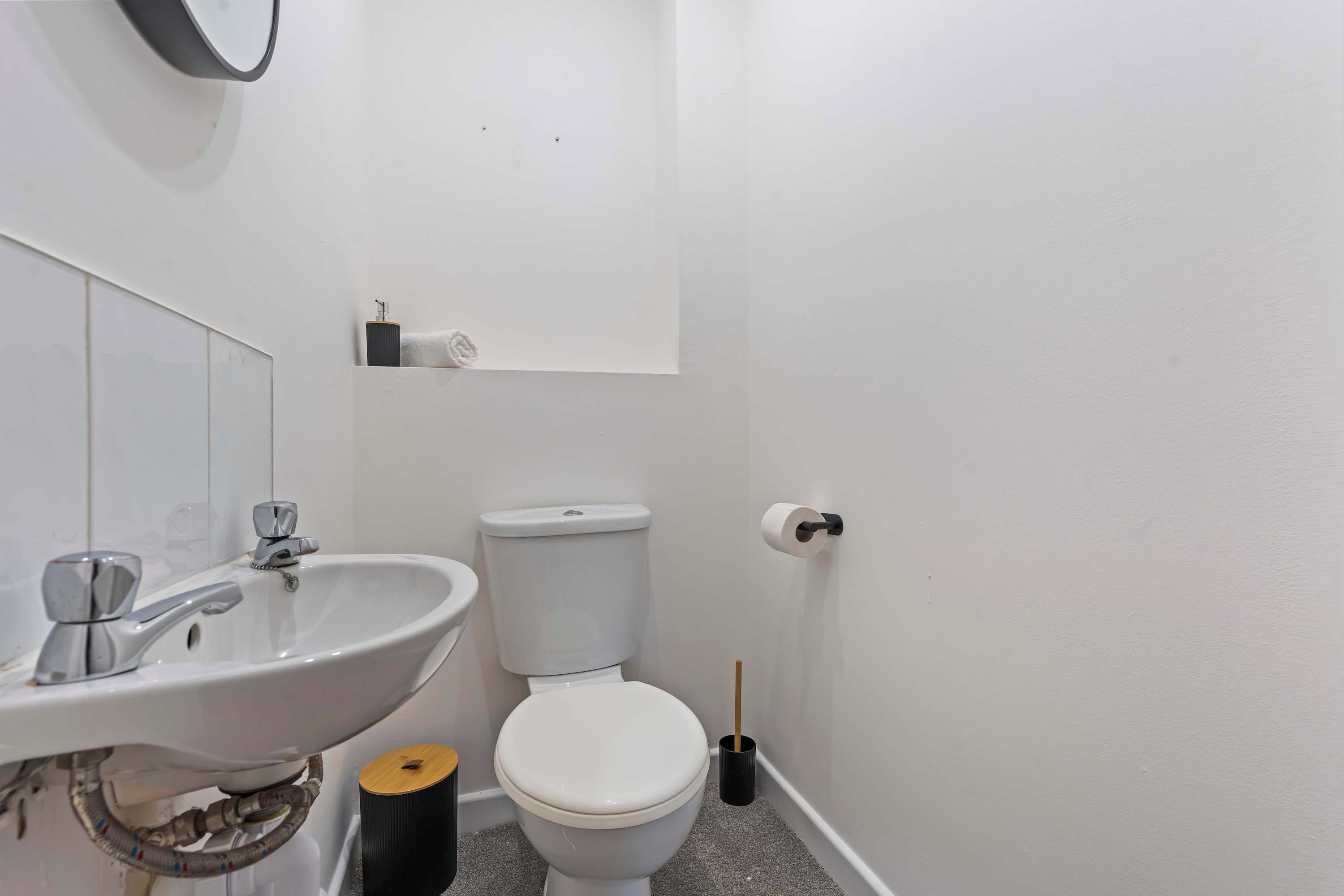 Ein kleines Badezimmer mit einem weißen Waschbecken, einer Toilette und einem Spiegel über dem Waschbecken.