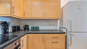 A kitchen with wooden cabinets, a Bosch refrigerator, and a black countertop. - City Haven Liverpool | 3BR w/ Parking (Merseyside)