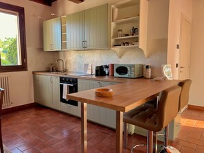 A kitchen with light green cabinets, a wooden table, a microwave, and a coffee machine. - Dolce Collina Holiday Home,
Sunset terrace & vineyard views, near Bologna/Imola (Dozza)