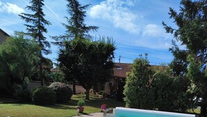 A rectangular swimming pool with clear blue water, surrounded by a tiled deck and bordered by trees and shrubs. - Appt, with private outdoor space with barbecue, swimming pool (Aigueperse)