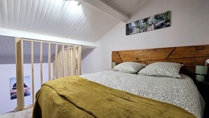 A bedroom with a bed, wooden headboard, and a painting on the wall. - Appt, with private outdoor space with barbecue, swimming pool (Aigueperse)