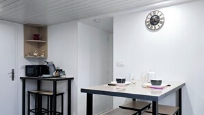 A modern kitchen with a white interior, a black-framed table, and a wall-mounted clock. - Appt, with private outdoor space with barbecue, swimming pool (Aigueperse)