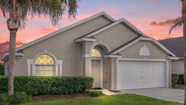 A single-story house with a garage, a front entrance with a door, and a driveway. - Delightful Family Pool Villa in Glenbrook with 4 Bedrooms & 3 Bathrooms (Clermont)