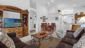 A living room with a TV, wooden furniture, a dining table, and a sofa. - Delightful Family Pool Villa in Glenbrook with 4 Bedrooms & 3 Bathrooms (Clermont)