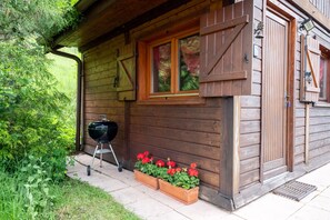 Eine Holzhütte mit Fenster, Grill und Blumenkästen.