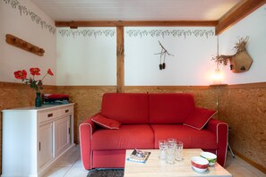 Un sofá rojo, un armario blanco y una mesa con vasos y fuentes.
