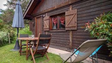 Une cabane en bois avec une terrasse, une table et des chaises, et un parasol.