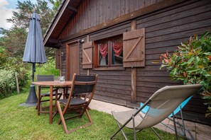 Eine Holzhütte mit einer Terrasse, einem Tisch mit Stühlen und einem Sonnenschirm.