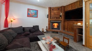 Un salon avec un canapé, une cheminée, un téléviseur et un tableau accroché au mur.