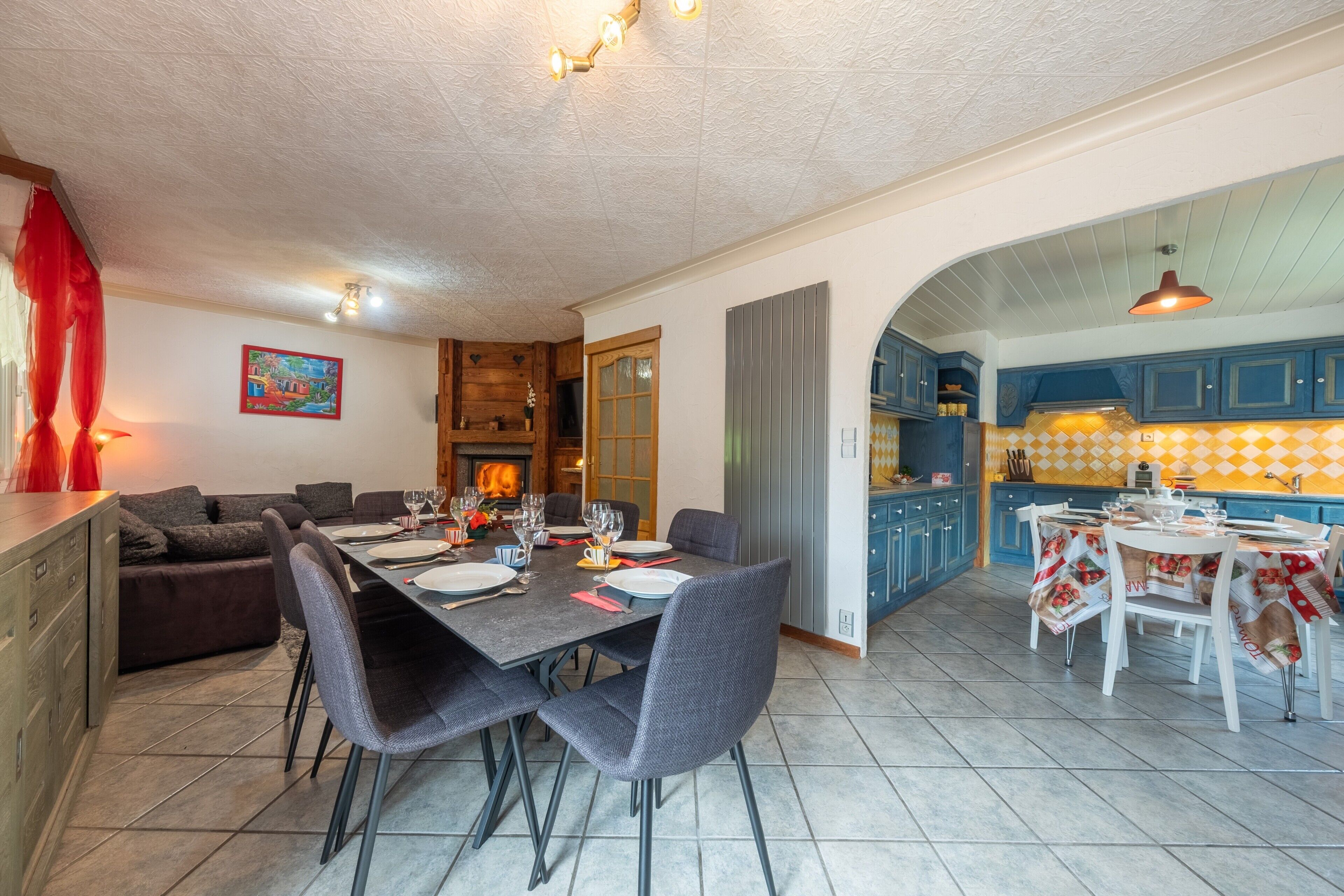 A dining area with a table set for four, a kitchen with blue cabinets, and a fireplace.